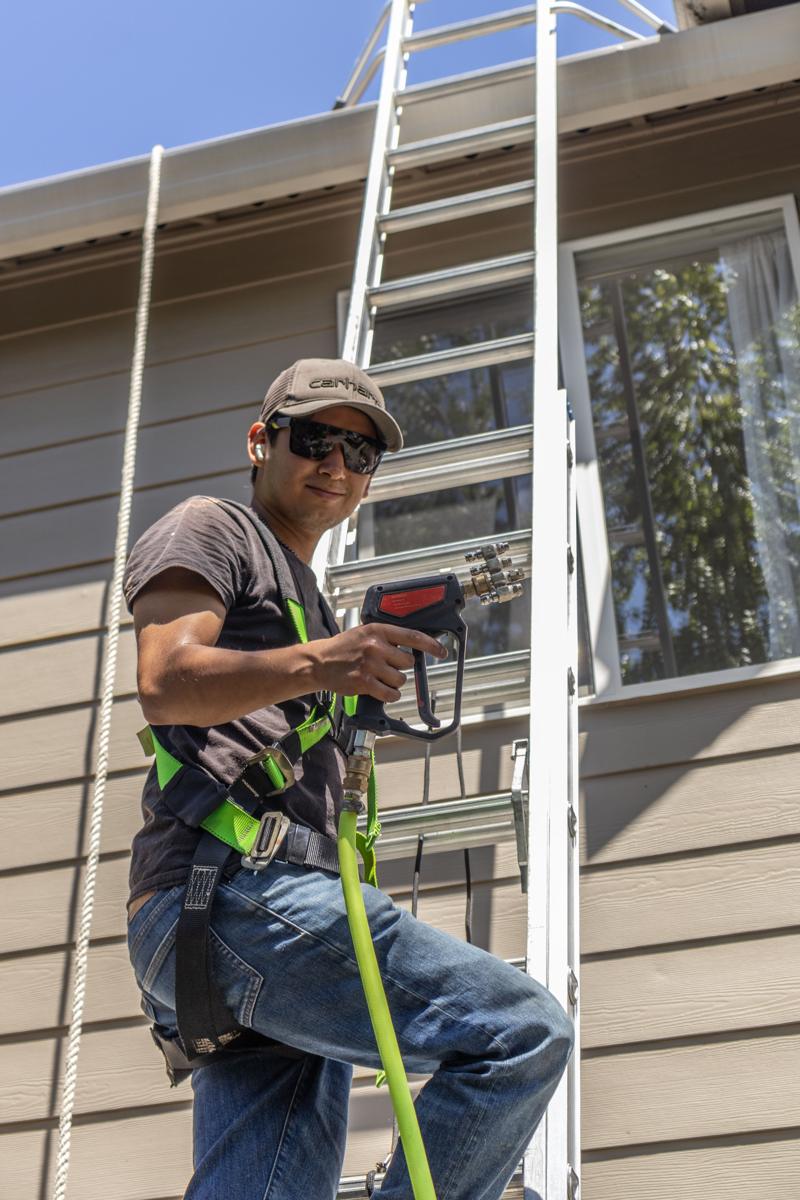 Valley Lights crew member on a ladder cleaning upstairs windows