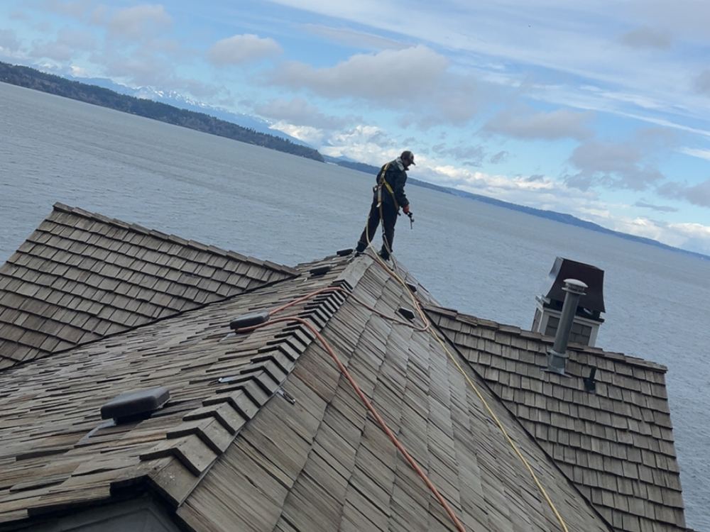 Cleaning a cedar shake roof above Puget Sound
